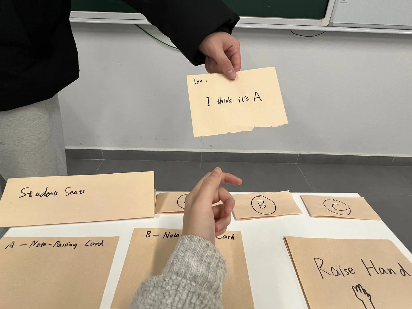 A note held up in reply beside the raise-hand card on the desk