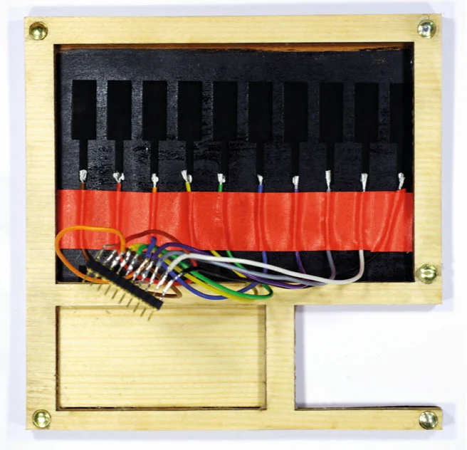 Rear of a wild cherry veneer panel with ten black laser-engraved touch buttons, each wired to a connector