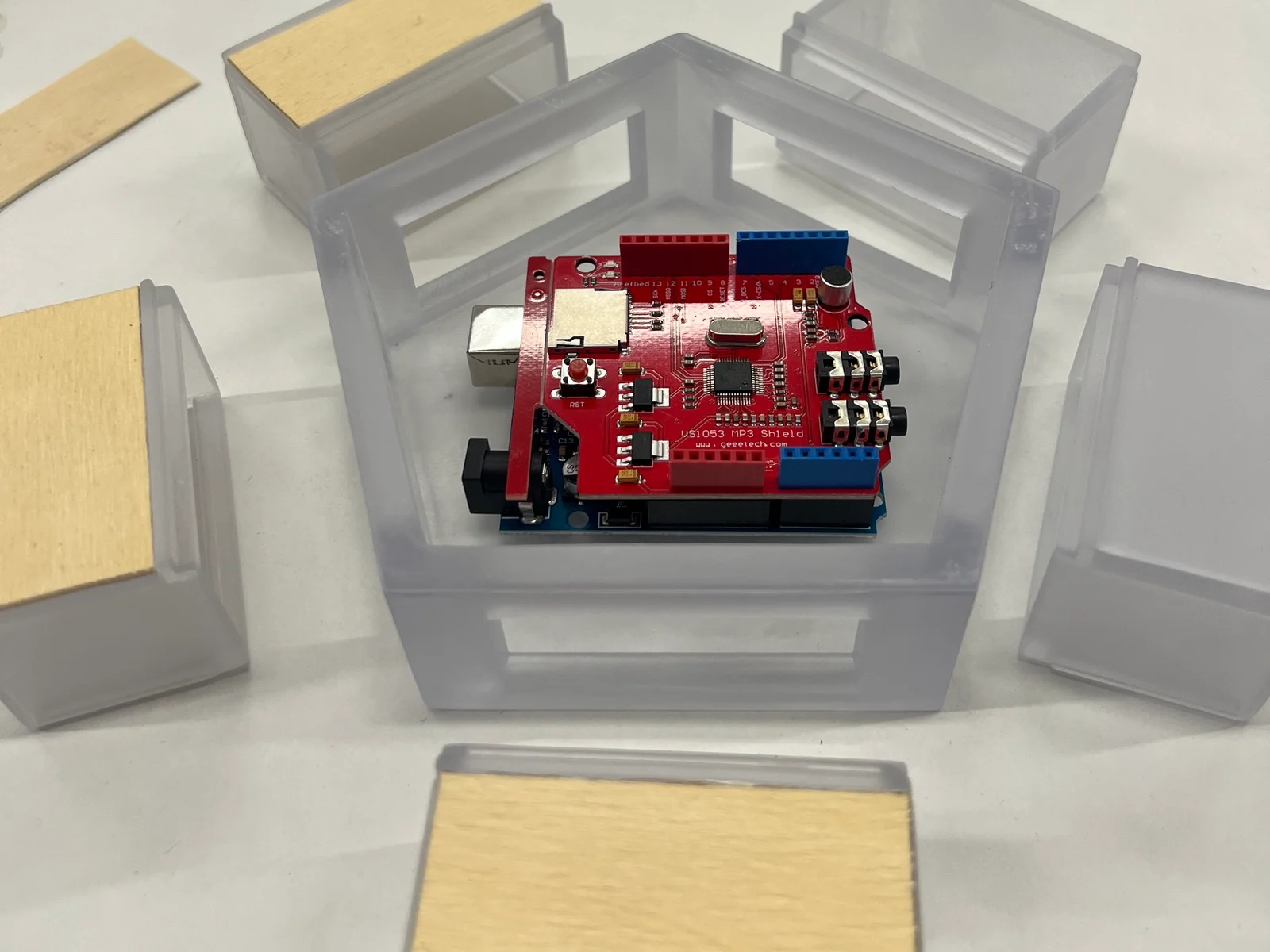 3D-printed translucent modules with wooden tops around an Arduino with a red shield in the pentagon centre